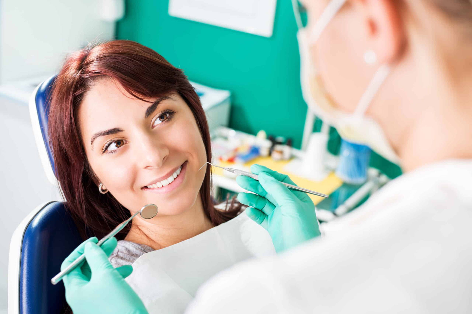 A woman seated in a dental chair receiving dental care from a professional.